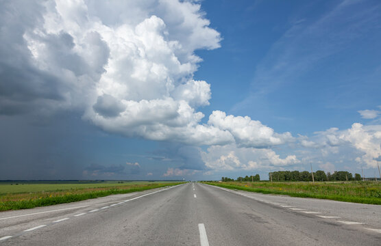 Road in the field under blue sky and clouds.
Beautiful view of an empty highway in Siberia in the countryside under a stormy sky full of clouds.