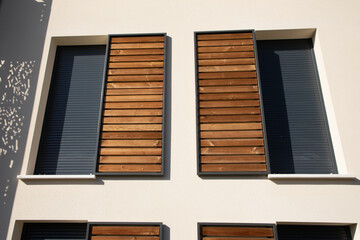home windows with modern wooden brown sliding shutters in house beige new facade apartment building