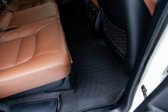 Clean car floor mats of black rubber under rear passenger seat in the workshop for the detailing vehicle dry cleaning. Auto service industry. Interior of sedan.