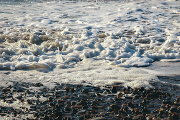 Close-up of a wave on the Black Sea coast. Sea foam of a coastal wave on a sandy beach in close-up....