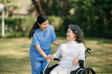 Obraz premium Elderly asian senior woman on wheelchair with Asian careful caregiver and encourage patient, walking in garden. with care from a caregiver and senior health insurance...