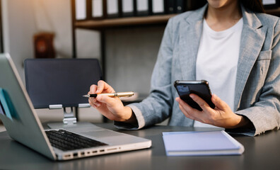 Businesswoman hand using smart phone laptop and tablet with social network diagram on desk as concept in morning light..