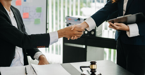 Woman lawyer hand and women client shaking hand collaborate on working agreements with contract documents at the modern office..