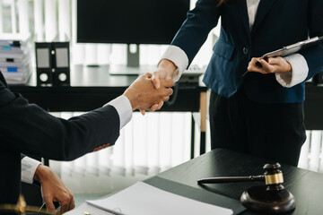 Woman lawyer hand and women client shaking hand collaborate on working agreements with contract documents at the modern office..
