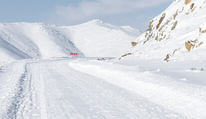Fototapeta na wymiar winter road with uphill turn and turn warning sign