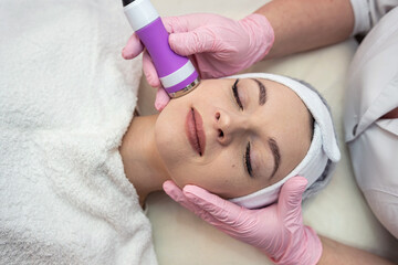 Cosmetologist doing ultrasound skin on face  tightening for rejuvenation at spa