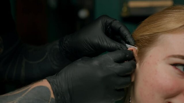 Piercing studio interior - piercing master makes a piercing to a girl ear piercing