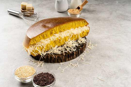 Martabak manis or terang bulan is indonesian sweet pancake, with yellow color and filled with chocolate chips, cheese, fruit jam, butter and peanut on concreate background.