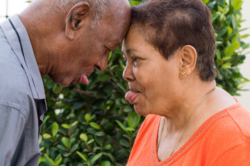 Senior couple touching foreheads together showing tongues to each other