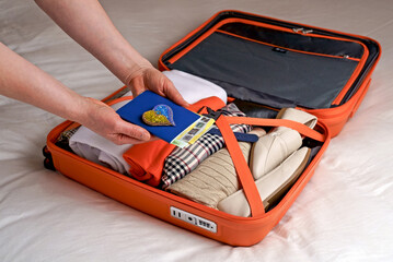 a woman puts clothes in a suitcase on the bed to prepare for a weekend trip. Pack your luggage and check if you forgot anything before your trip.