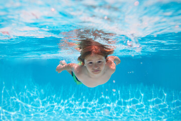 Underwater child swims in pool, healthy child swimming and having fun under water. Summer kids activity, watersports.