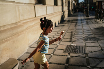 Child playing in the street with an ice cream in her hand