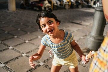 Girl making faces to the camera while playing with an ice cream in her hands