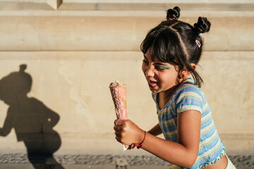 Child running with an ice cream in her hand.