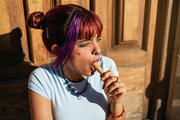 Woman with colorful hair eating an ice cream at sunset.