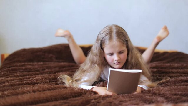 Little girl reads a book and thinks. Concept of learning from home