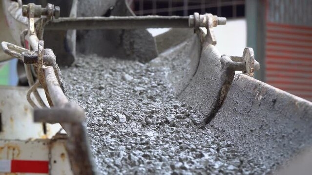 Cement falling from a conveyor into a container at a construction site, view of the production of a concrete mixer. Handheld closeup shot.
