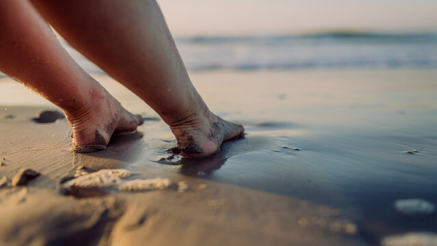 Close-up of woman with her feet in sea.