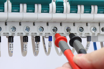 Measurement of electrical circuit parameters using a multimeter in an electrical switchboard.