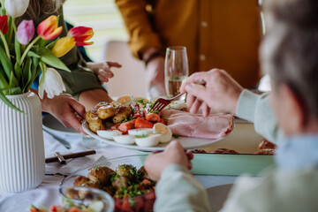 Close up of muligenerational family serving Easter dinner together. - obrazy, fototapety, plakaty