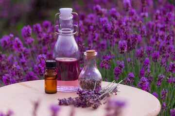 jars with lavender oil, lavender flowers, on the background of a lavender field.