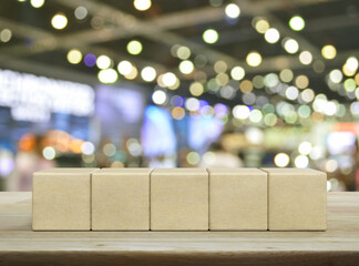 Five wood block cubes on wooden table over blur light and shadow of shopping mall
