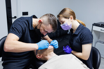 An orthodontist with an assistant treats teeth using dental instruments. Dental office. Orthodontic treatment of teeth