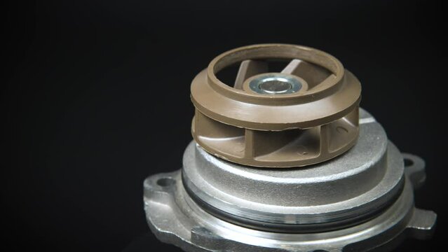 Auto parts car spare parts on a black background. The new ICE water cooling pump rotates on a turntable around its axis. Auto parts store. Engine car details