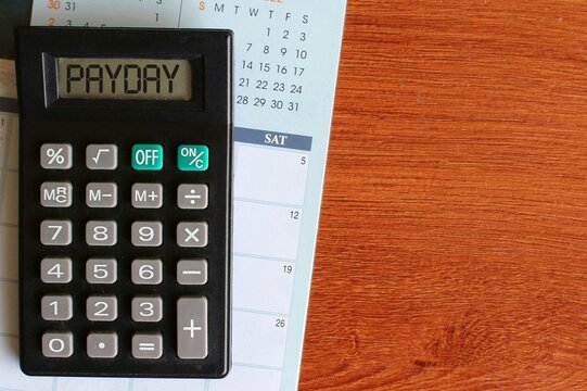 Top view image of calendar and calculator with text PAYDAY. Finance concept