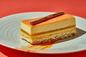 Passion fruit and mango mousse cake in a plate on an orange background. Monochrome food poster