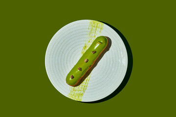 Pistachio eclair with green glaze in a plate. Monochrome food poster