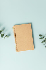 Notebook and flowers on blue background. Flat lay top view copy space mockup