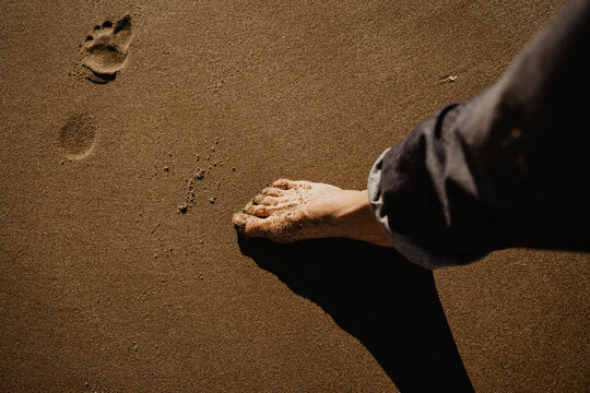 Bare foot in the sand with rolled jeans