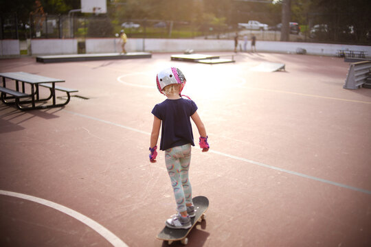 backside view of girl at golden hour skateboarding at skatepark