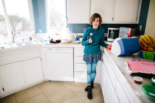 Girl in her messy kitchen holds a fork with mochi