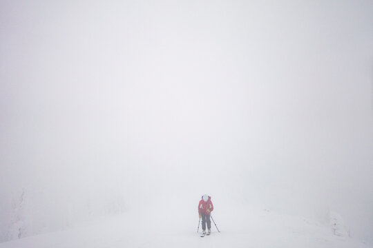 A woman backcountry skier touring a whiteout ridge in Montana