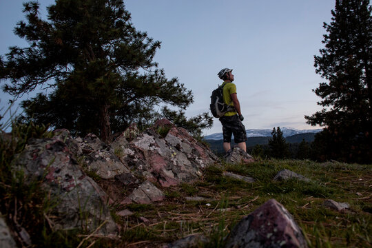 A male mountain biker at dusks takes in the view of Lolo Peak, Montana