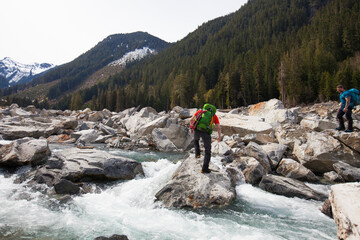 Backpacker crosses a raging river in the wilderness.