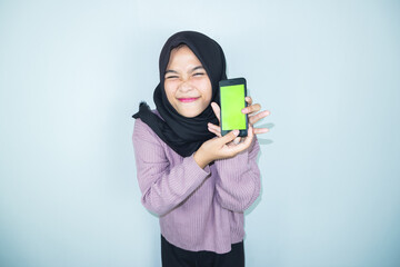 Excited beautiful Asian woman hijab showing blank screen mobile phone isolated over white background.