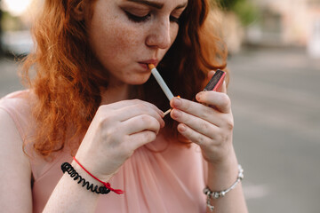 Young red head woman igniting cigarette with matchsticks