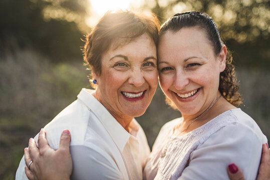 close up portrait of adult mother and daughter embracing and smiling