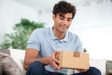 young man sitting on sofa with parcel