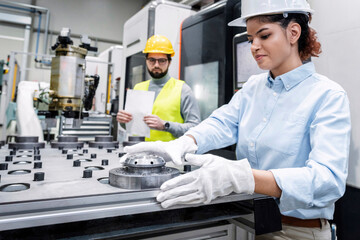 Smiling businesswoman working with machine part in factory