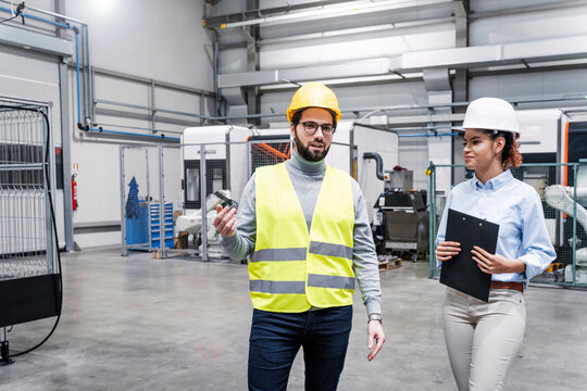 Smiling engineer talking with colleague in factory