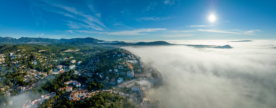 Spain, Majorca, Santa Ponca, Aerial panorama of thick fog floating in front of coastal town