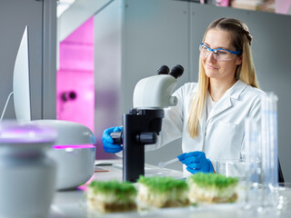 Smiling young scientist working with microscope in laboratory
