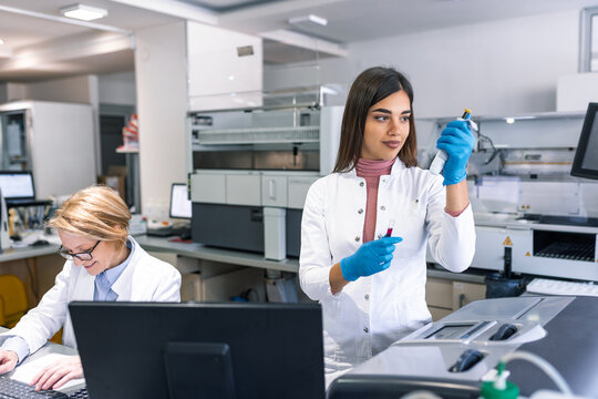 Portrait of female scientist with a pipette analyzes a liquid to extract the DNA and molecules in the test tubes in laboratory. Concept of research,biochemistry, pharmaceutical medicine