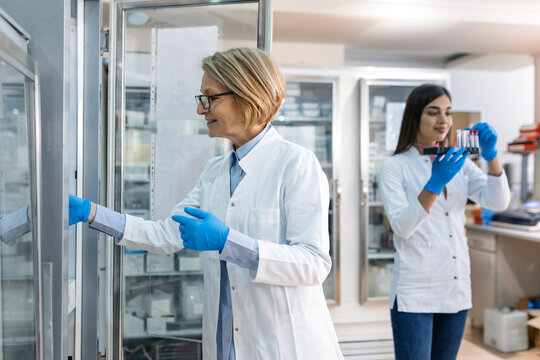 Scientist holding experiment sample in laboratory medical freezer.