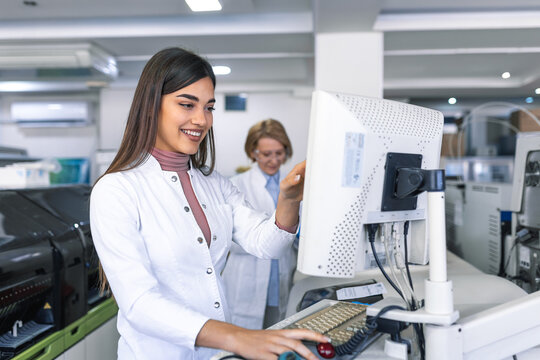 Female Scientists Programs Medical Equipment with Personal Computer. Team Of Professionals Working in Pharmaceutical Research Modern Laboratory.