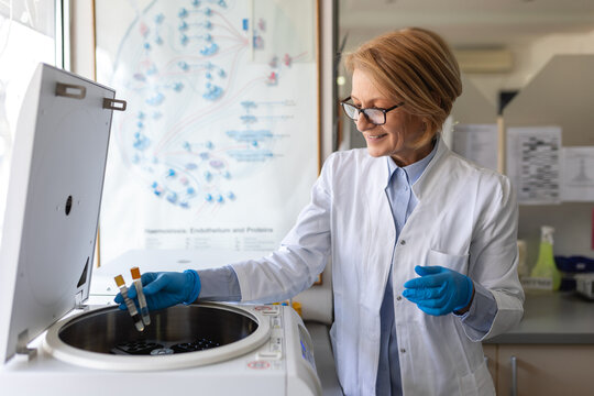 Technician loading a sample to centrifuge machine in the medical or scientific laboratory